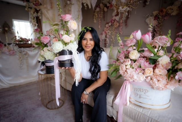 Dayana of Day Dream Affairs, smiling among her blush floral arrangements